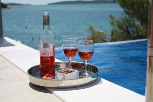 two glasses of wine and a bottle on a tray next to a pool at Pinna Nobilis Apartments - Ground Floor in Brodarica