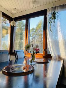 un tavolo da pranzo con un vaso di fiori sopra di Voionmajoitus a Ylöjärvi