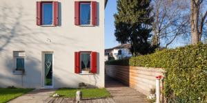 a white house with red windows and a fence at Bed & Breakfast Canova in Treviso