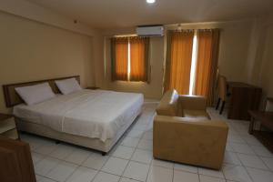 a bedroom with a bed and a chair and window at Apartemen Mutiara Bekasi by Alfa Rooms in Pekayon Satu +51 photos