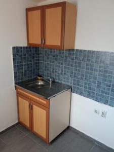 a kitchen with a sink and blue tiles on the wall at City Rooms 400m from Center in Mitrovica