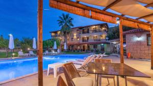 a patio with a table and chairs next to a swimming pool at Katerina-Maria Studios & Apartments in Vourvourou