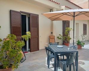 a black table and chairs with an umbrella on a patio at West Sicily - Villa with Garden and Parking in Marsala +31 photos