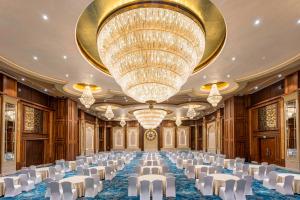 卡尔贾特Radisson Blu Plaza Resort & Convention Centre Karjat的宴会厅里摆放着白色的椅子和一盏巨大的枝形吊灯 更多37张照片