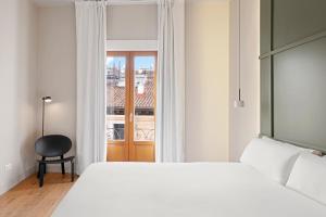 a bedroom with a bed and a window and a chair at B&B HOTEL Apartamentos Madrid Centro Fuencarral 46 in Madrid