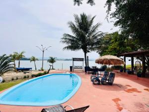 a swimming pool with chairs and a view of the water at Casa da Ilha in Ribeirão Claro