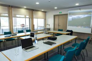 a classroom with tables and chairs and a projection screen at Auberge Du Mehrbachel in Saint-Amarin