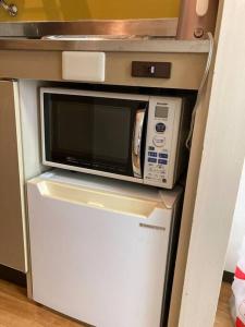 a microwave on top of a refrigerator in a kitchen at JKhouse4 in Fukuoka