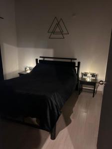 MachetáVibes Home的一间卧室配有一张床和两张带蜡烛的桌子。