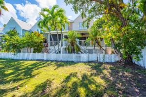 a house with a white fence and palm trees at Cabana at the Golf Club - Monthly Rental in Key West