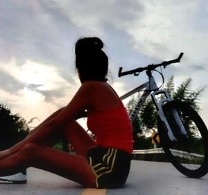 a woman sitting on the ground next to a bike at CHILLI's Homes2 in Chiang Mai