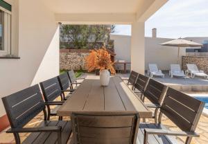 a wooden table with chairs and a vase on it at House Dali in Ražanac