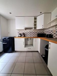 eine Küche mit weißen Schränken und einem Fliesenboden in der Unterkunft Le Duplex-suite Joséphine in Brüssel
