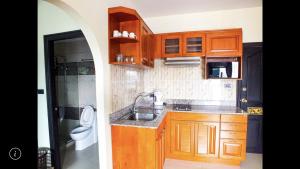 a kitchen with wooden cabinets and a sink and a toilet at Junior apartment in Pattaya