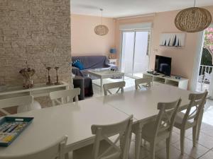 a living room with a white table and chairs at Belle villa spacieuse avec piscine privée, semi climatisée- 10 couchages, wifi, proche canal du midi et à 4 km de la mer LXPIN7 in Portiragnes
