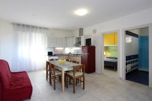 a kitchen with a table and a red refrigerator at Elsa bilocale vista spiaggia in Rosolina Mare