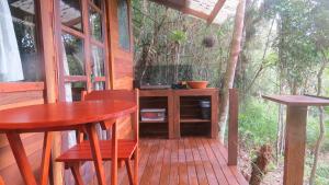 a porch with a table and chairs on a deck at Cabanas sítio Ancestral in Morretes