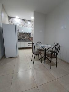 una sala da pranzo con tavolo, sedie e frigorifero di Aconchego 2 a Dourados