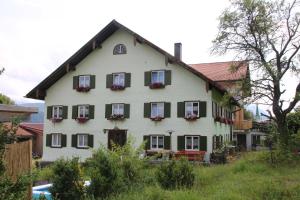 a white house with green shutters and flowers on it at Wellnesshof Müller Vorderburg in Vorderburg
