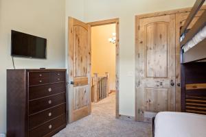 a bedroom with wooden doors and a dresser and a tv at Spacious Retreat, Sleeps 7, Minutes to Skiing, Private Hot Tub, Scenic Views, Ultimate Relaxation! in Park City
