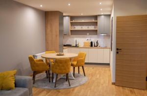 a dining room with a table and chairs and a kitchen at Liberte Apartments in Sombor