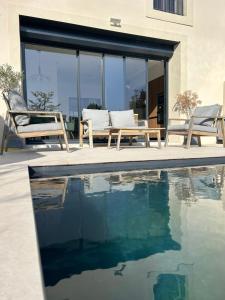 a pool with two chairs and a bench next to a house at Maison élégante avec piscine in Tournon-sur-Rhône