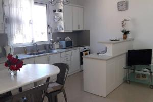 a kitchen with white cabinets and a table and a window at Simos Apartment in Gjirokastër