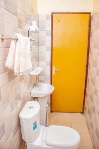 bagno con servizi igienici e porta gialla di BelleVille Residence a Bobo-Dioulasso