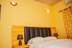 una camera con un letto con un testata nera e due lampade di BelleVille Residence a Bobo-Dioulasso