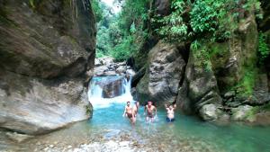 three men standing in the water near a waterfall at D-SA's Stay in Gorubathān
