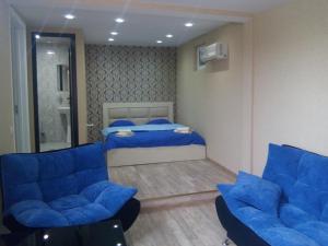 a bedroom with a bed and two blue chairs at GTNL Aparthotel in Tbilisi City