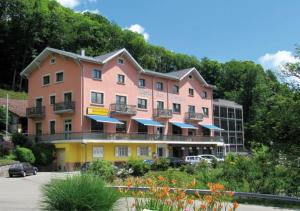 ein großes rosa und gelbes Gebäude mit einem Parkplatz in der Unterkunft Hotel Restaurant Perle Des Vosges in Muhlbach-sur-Munster