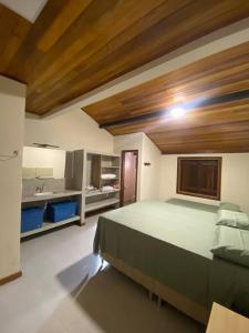 a bedroom with a large bed and a kitchen at Casa Portas do Mar in Marau
