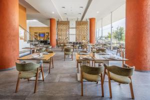 a restaurant with wooden tables and chairs and orange columns at Hotel México Plaza Querétaro in Querétaro