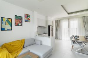 a white living room with a couch and a table at Friendly Kamala Garden View in Kamala Beach