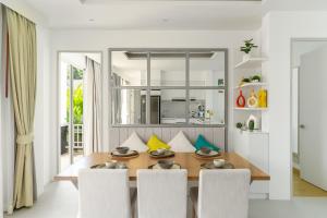 a dining room with a wooden table and white chairs at Friendly Kamala Garden View in Kamala Beach