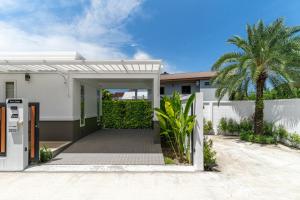 a white house with a gate and a palm tree at Friendly Kamala Garden View in Kamala Beach