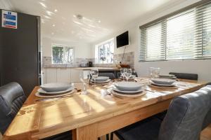 a kitchen with a wooden table with plates and glasses at Surf Break in Wadebridge