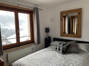 a bedroom with a bed with a mirror and a window at Morzine apartment, perfect ski and summer base for 8 in Montriond