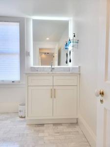 Un baño blanco con lavabo y espejo. en Spacious West End Loft in Charming Family Home, en Portland
