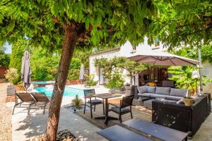 a patio with a table and umbrella next to a pool at Logis de La Brumanderie in Fontcouverte