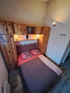 a small bed in a small room with wooden cabinets at Bolquère appartement de plain-pied 1 à 4 personnes in Bolquere Pyrenees 2000
