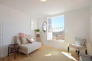 een woonkamer met een stoel en een raam bij Stay local in Alfama! Deolinda central Home, amazing view in Lissabon
