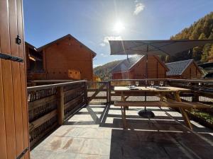 a wooden deck with a table and an umbrella at La Foux D'Allos Rez de jardin plein sud 50m des remontées mécaniques in La Foux