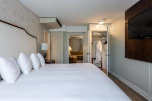 a bedroom with a white bed with a flat screen tv at The Georgetown Inn in Washington, D.C. +59 photos