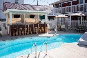 a swimming pool with chairs and a house at The Burgundy Inn Hotel and Apartments in Ocean City