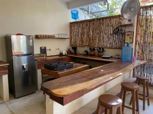 a kitchen with a counter and a refrigerator and stools at Casa Selva casa privada con alberca, en Punta in Brisas de Zicatela