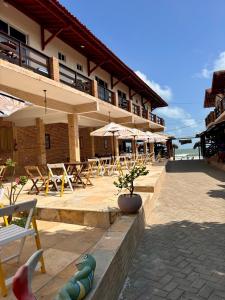 a resort with tables and chairs and a building at Pousada e Restaurante Altas Horas Beach in Itapipoca