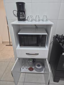 a microwave on a white shelf in a kitchen at Apartamento próximo Cambui in Campinas