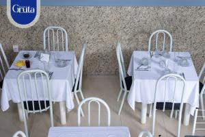 two white tables and chairs with dishes on them at Hotel Pousada da Gruta in Caratinga